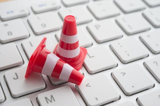 Close up orange white traffic warning cones or pylon on keyboard computer