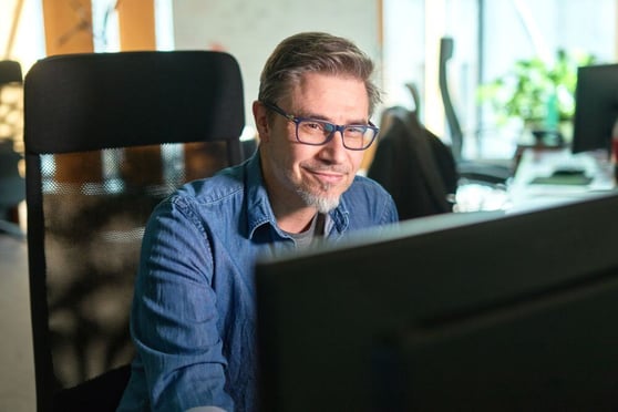 A man working at a desktop computer, representing a content creator learning how to create unique content.