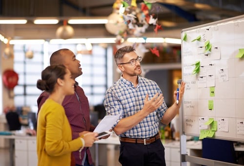 Team discussing strategy at a whiteboard during a planning session about everything you need to know about SEO.