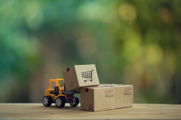 Mini forklift lifting boxes with shopping cart icon, symbolizing e-commerce logistics in b2b advertising platforms.